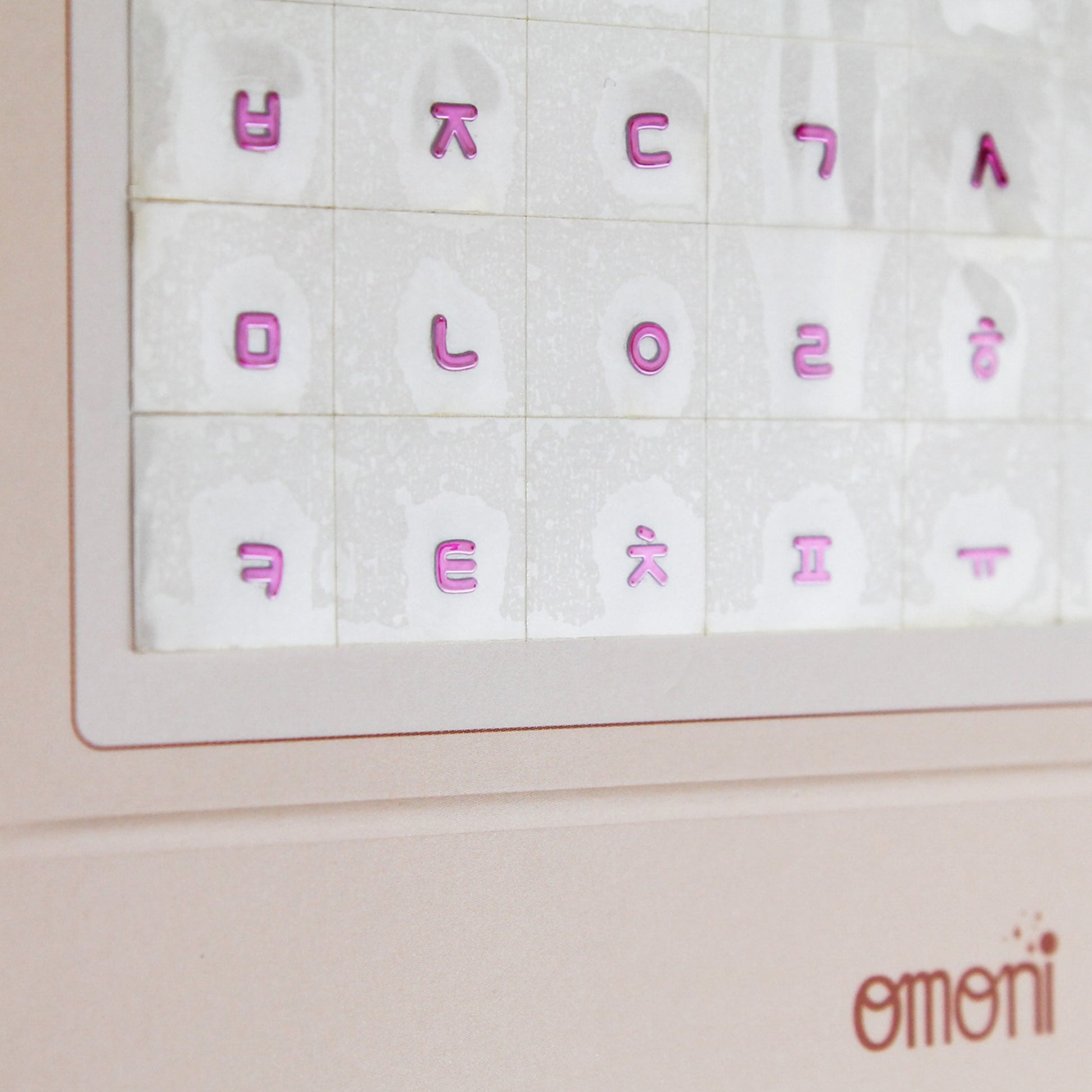 A zoomed image showing a laptop keyboard packaging showcasing the Korean seamless die-cut sticker set. Seamless die-cut Korean Hangul keyboard sticker with Korean alphabet letters for learning Korean, typing practice, vocabulary building and beginner Korean language lessons. Keyboard Sticker Metallic Pink Color in a angled photo.