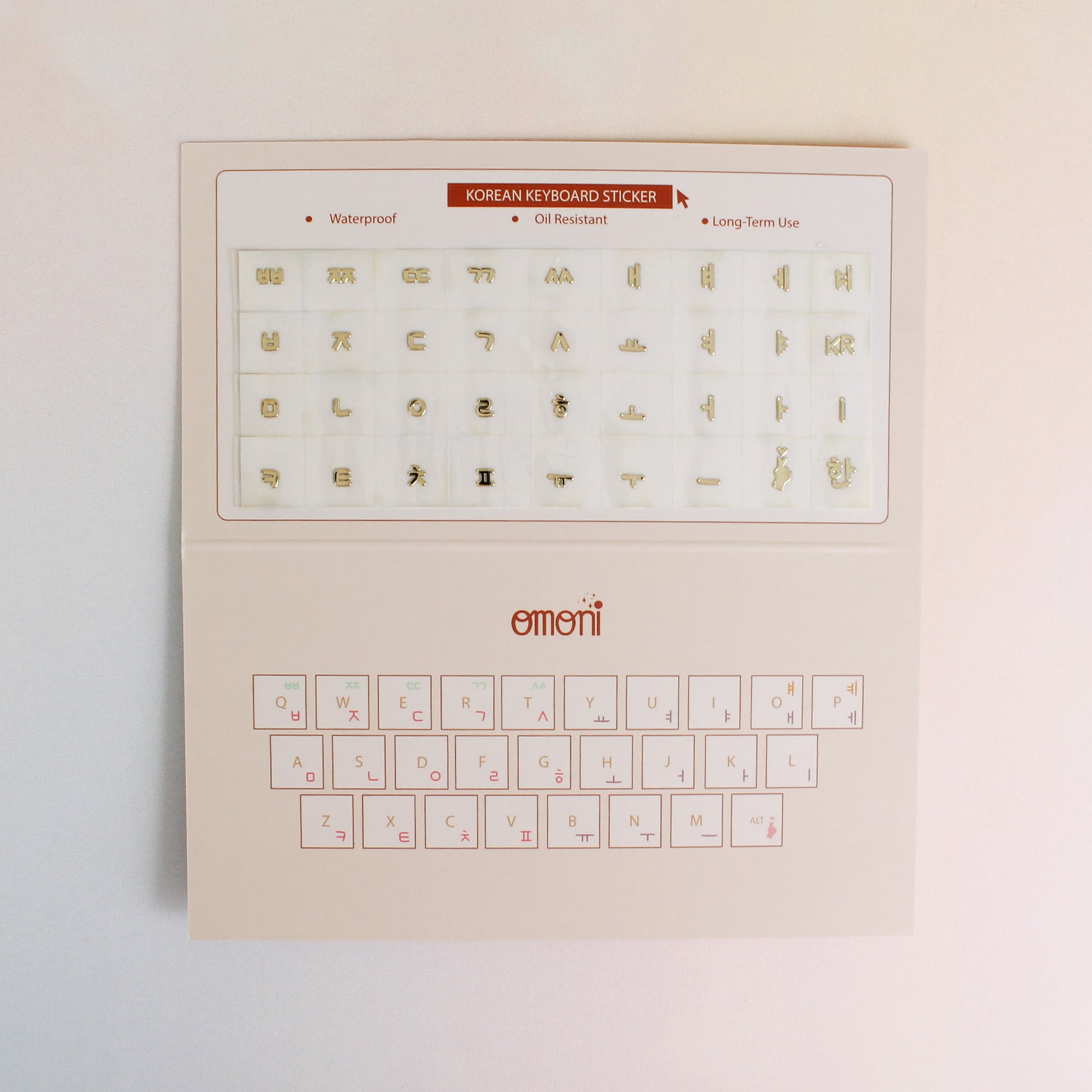 An image showing a laptop keyboard packaging with Korean seamless sticker set. Seamless die-cut Korean Hangul keyboard sticker with Korean alphabet letters for learning Korean, typing practice, vocabulary building and beginner Korean language lessons. Metallic gold.