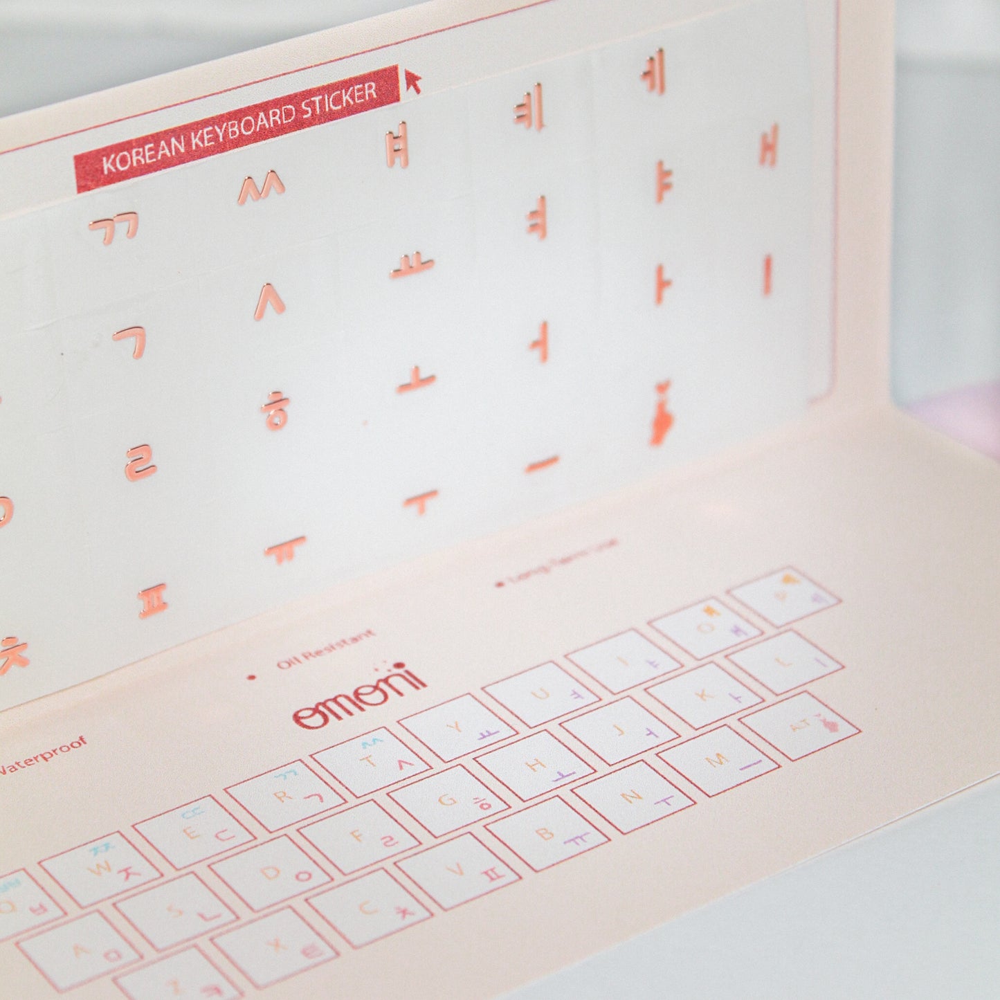 A zoomed image showing a laptop keyboard packaging showcasing the Korean seamless die-cut sticker set. Seamless die-cut Korean Hangul keyboard sticker with Korean alphabet letters for learning Korean, typing practice, vocabulary building and beginner Korean language lessons. Keyboard Sticker Metallic Rose Gold Color in a angled photo.