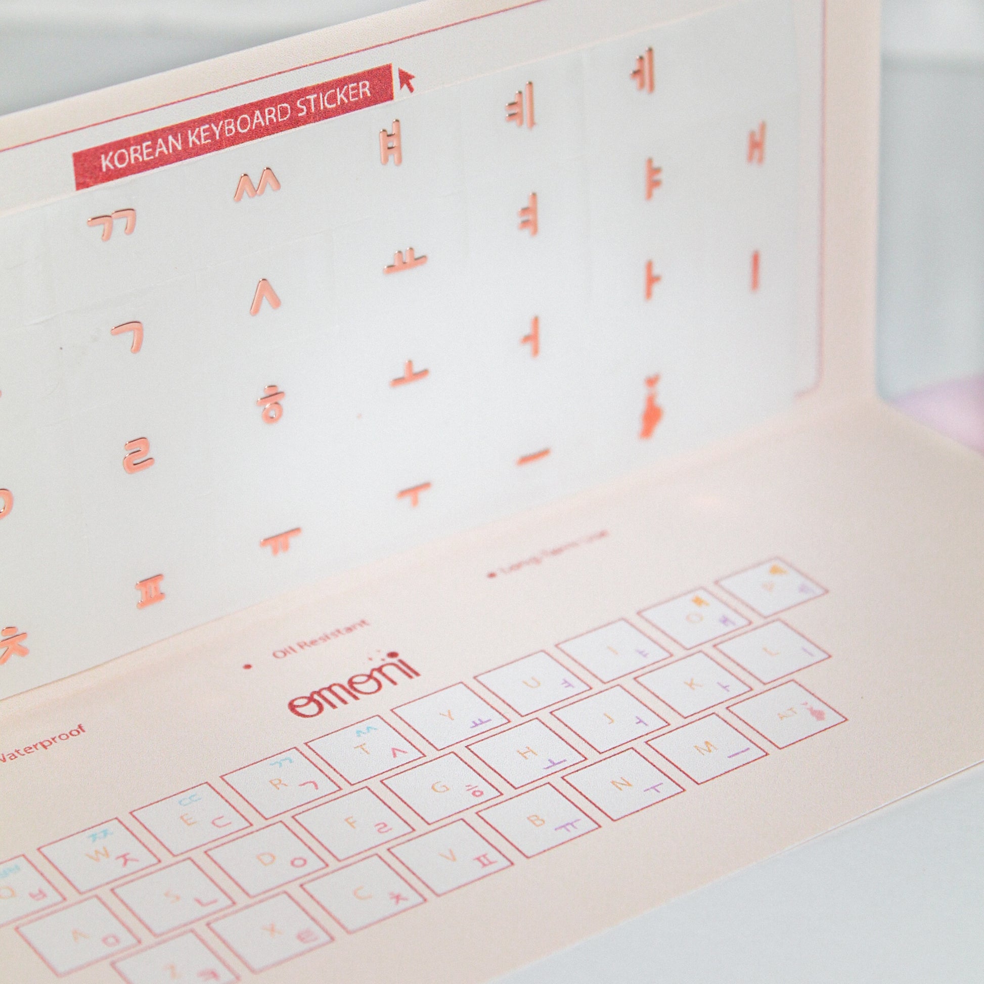 A zoomed image showing a laptop keyboard packaging showcasing the Korean seamless die-cut sticker set. Seamless die-cut Korean Hangul keyboard sticker with Korean alphabet letters for learning Korean, typing practice, vocabulary building and beginner Korean language lessons. Keyboard Sticker Metallic Rose Gold Color in a angled photo.